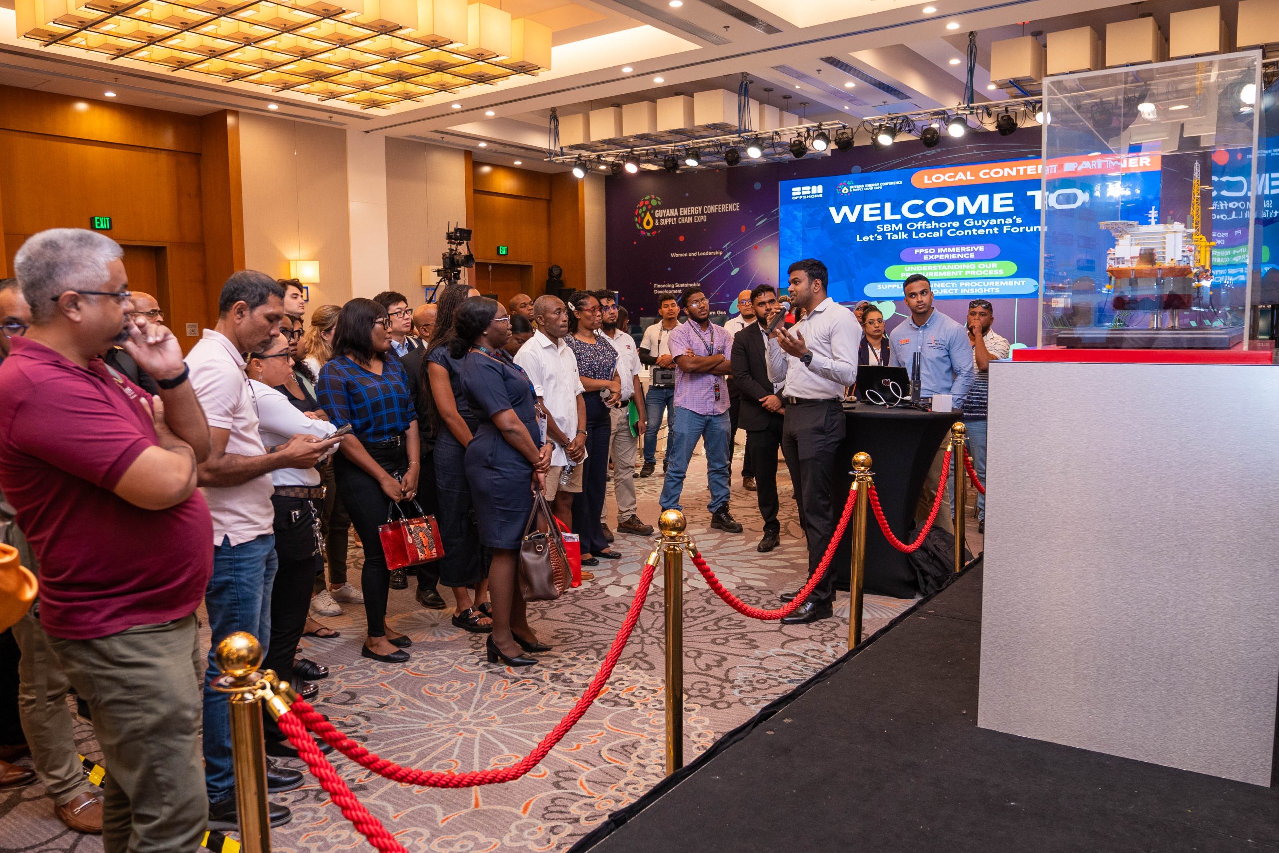 Visitors at SBM Offshore Guyana’s Let’s Talk Local Content Forum, beside an FPSO model